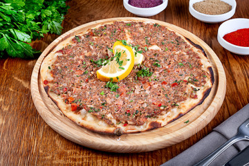 Turkish pide on wooden plate and wooden background. Traditional turkish food. Green, meat, bread. Closeup view 45 degree. Halal food