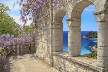 Beautiful view of the loggia and on the sea, a loggia of natural stone the masonry with arched windows ,  blossoming Wisteria on the loggia