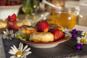 Cottage cheese pancakes, curd fritters with fresh berries strawberries with daisy flowers