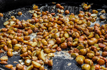 potatoes are fried in a large frying pan on fire