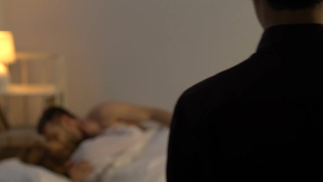 Shocked man looking at unfaithful girlfriend cheating with lover in bed, crisis