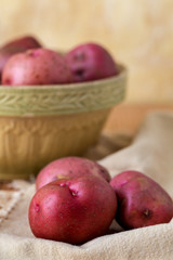 Fresh, Raw, Red Potatoes in a Vintage Bowl on a Wood Table with Yellow Plaster Wall in the Background