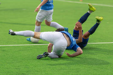 Football players tumbling on the football field. Falling players in the fight for the ball