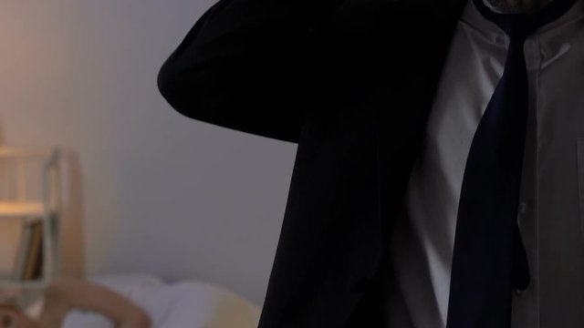 Man in business suit leaving room with sleeping mistress, unfaithful husband