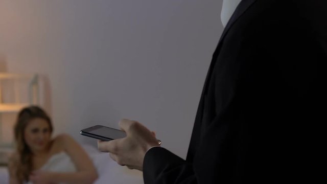 Unfaithful husband talking on smartphone with wife and walking to mistress