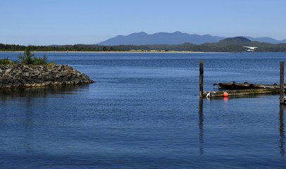 View across the bay towards islands and Mountains, float plane landing in the bay, seen from Tofino, Vancouver Island British Columbia Canada