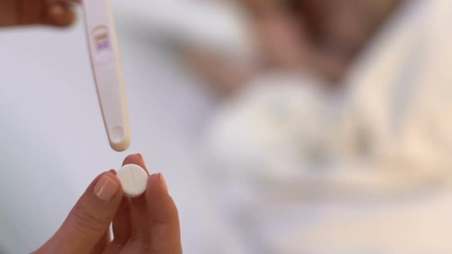 Positive pregnancy test in female hand, woman taking abortion pill, wrong choice