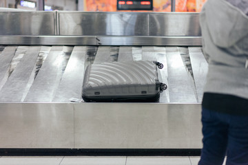 A traveler waiting for a luggage on the belt at the airport.
