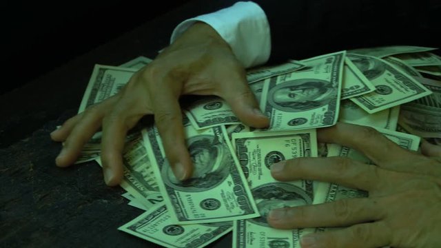 US paper currency,business concept.
Lucky businessman in pinstripe suit gaining and sweeping lots of us dollar banknotes at old wooden table, side view HD slow motion.