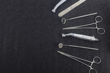 Dental instruments: mirror and other tools on dark background.