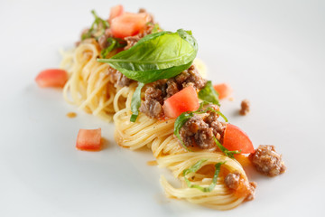 Delicious spaghetti with meat and tomato served on a white plate. Closeup