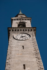 Obraz premium Tower bell of the main church seen from below with blue sky in Pinzolo