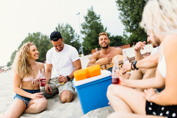 Group of attractive young people enjoying at beach, drinking and toasting.