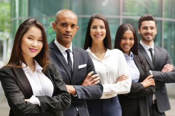 Portrait of business people of different ethnic backgrounds dressed in suits, they smile and cross...