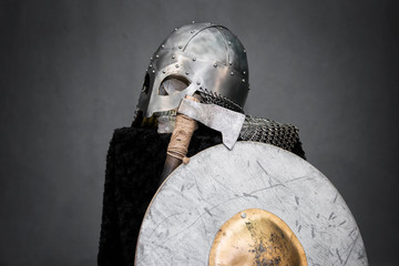  Skull in a Viking helmet, on a black pedestal, in front of him an ax and a round shield.  Studio...