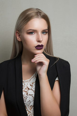 Closeup portrait of luxurious blonde model with purple lips wearing black jacket and lace blouse