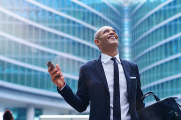 An business man in a suit and tie is happy and smiling while sending messages, working emails or calling using the phone. Concept of: technnology, network, success.