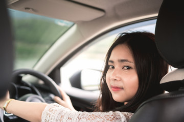 Obraz na płótnie Canvas Young asian woman in casual wear hold steering wheel and looking at passengers in back seat.