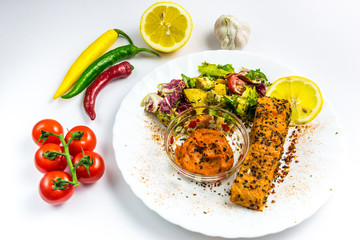 Salmon with vegetabes on white plate