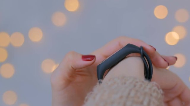 Young woman using wearable fitness tracker. Warm bokeh light background. Entertainment and technology concept. Close up shot of woman hand with smartwatch