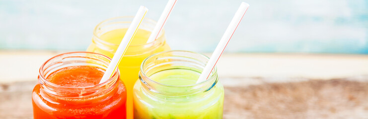 freshly squeezed fruit juice, smoothies yellow orange green on a dark wooden background Copy space. Banner concept .