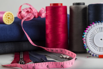 Sewing materials are colorful bobbins,tape measure and scissors on the white background.