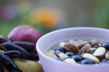 Healthy breakfast: muesli with grapes and nuts, and fresh fruit are on a blurred background of green nature. Concept: healthy food & natural breakfast.