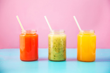 freshly squeezed fruit juice, smoothies yellow orange green on bright blue and pink background Copy space