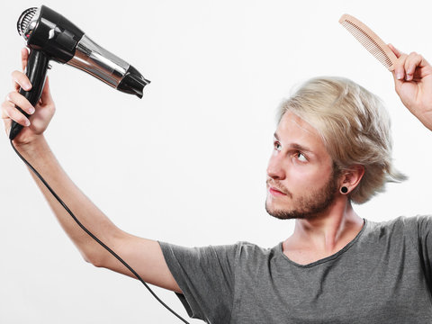 Young man drying hair with hairdryer