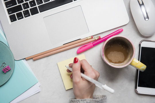 Woman writing on notepad at desk