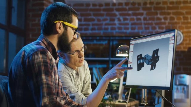 Two men designing and constructing workpiece on computer using three-dimensional program