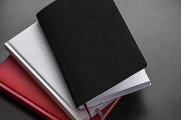 Office dark table. Mock up book blank black, red, white, leather cover for magazine, booklet, brochure, diary, business portfolio mock-up design template on black background. Flat lay, top view, copy 