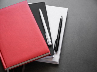 Office dark table. Mock up book blank black, red, white, leather cover for magazine, booklet, brochure, diary, business portfolio mock-up design template on black background. Flat lay, top view, copy 