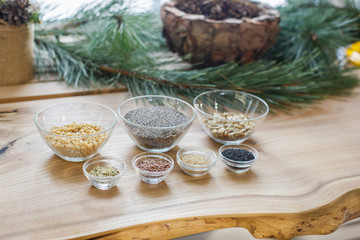 organic flax and pumpkin seeds, black and white sesame, chia seeds, pine nuts in glass bowls on a wooden table. Health and super food to boost immune system or body care concept