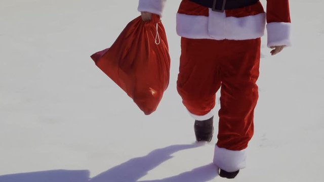 Santa Claus with bag of presents walk on the snow