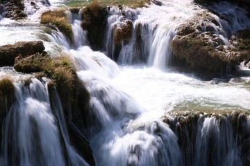 Naturalny wodospad górski spływający kaskadą po kamieniach i zieleni