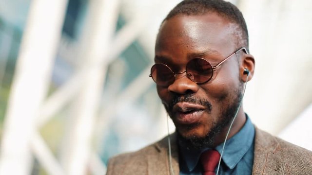 African American man talks on video-call walking along the street. Business, people, music, technology, leisure and lifestyle concept