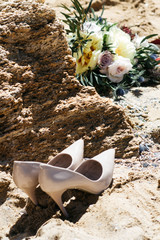 wedding shoes, a bride's bouquet on a rock background