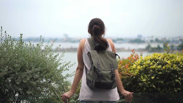 Young woman with backpack enjoying view of the landscape from the hotel. Travel concept. Back view