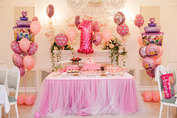 Delicious pink candy bar of birthday party for one year old girl. dessert table. Table with colorful sweets, candies, dessert, macaroons. Candy Bar buffet with cupcakes at restaurant.