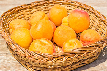 Ripe apricots in a basket on a wooden table
