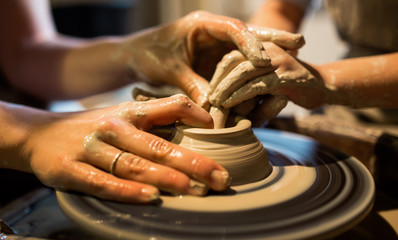 Master potter teaches the child to work on the Potter's wheel. Close up shot