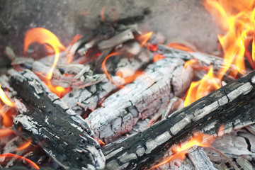 The hot coals with the tongues of flame in the old grill