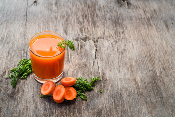 Fresh and healthy carrot juice in glass on wooden background. Top view. Copy space