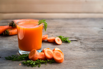 Fresh and healthy carrot juice in glass on wooden background. Top view. Copy space