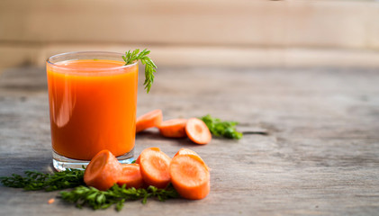 Fresh and healthy carrot juice in glass on wooden background. Top view. Copy space