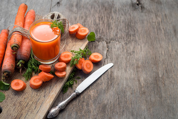Fresh and healthy carrot juice in glass on wooden background. Top view. Copy space