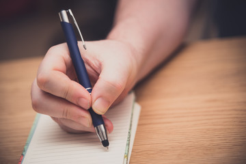 Man's hand writing on a notepad with a pen, copywriting concept