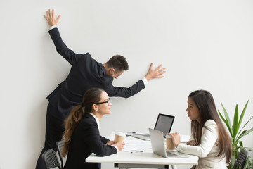 Businessman getting bored of dull work at team meeting, silly office worker leaning on wall...