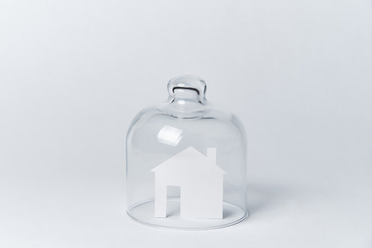 A House Made Of White Paper Under Glass On A White Background.